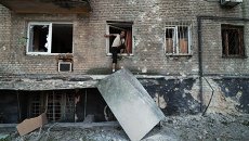 Мужчина выбирается через окно жилого дома в Донецке. Архивное фото Мужчина выбирается через окно жилого дома в Донецке. Архивное фото
