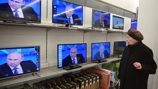 Посетительница магазина электроники в Москве смотрит телетрансляцию большой пресс-конференции президента России Владимира Путина Посетительница магазина электроники в Москве смотрит телетрансляцию большой пресс-конференции президента России Владимира Путина