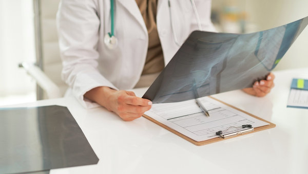 Врач изучает рентгеновский снимок пациента. Архивное фото