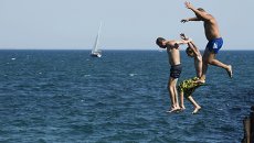 Мужчины прыгают в Черное море в городе Евпатория Мужчины прыгают в Черное море в городе Евпатория