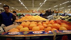 Продавец у прилавка с мандаринами из Турции. Архивное фото Продавец у прилавка с мандаринами из Турции. Архивное фото
