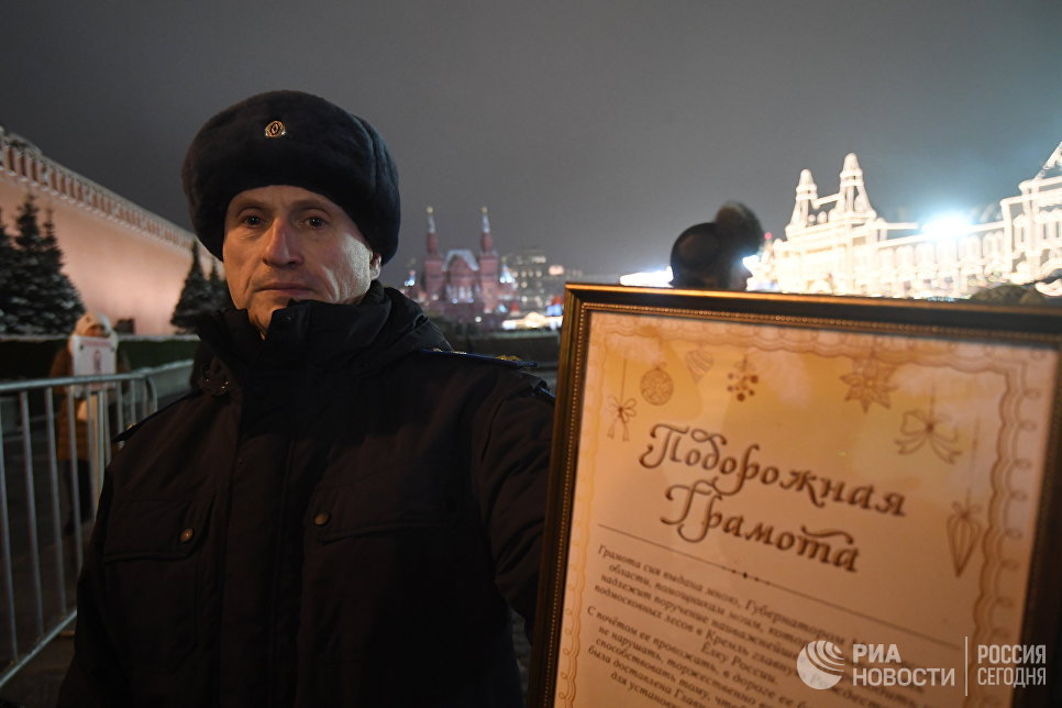 Сотрудник правоохранительных органов демонстрирует подорожную грамоту для проезда специального автопоезда с главной Новогодней елкой России на территорию московского Кремля Сотрудник правоохранительных органов демонстрирует подорожную грамоту для проезда специального автопоезда с главной Новогодней елкой России на территорию московского Кремля