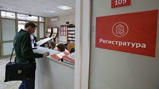 Посетитель у регистрационного стола в поликлинике. Архивное фото Посетитель у регистрационного стола в поликлинике. Архивное фото