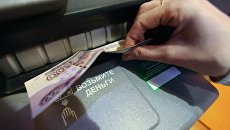 Женщина получает наличные деньги из банкомата. Архивное фото Женщина получает наличные деньги из банкомата. Архивное фото