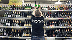 Продавец расставляет на полках бутылки шампанского вина. Архивное фото Продавец расставляет на полках бутылки шампанского вина. Архивное фото