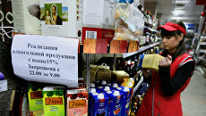Продавец супермаркета в отделе по продаже алкоголя. Архивное фото Продавец супермаркета в отделе по продаже алкоголя. Архивное фото