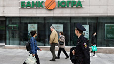 Прохожие у одного из филиалов банка Югра в Москве. Архивное фото Прохожие у одного из филиалов банка Югра в Москве. Архивное фото