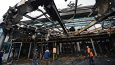 Рабочие у входа в киноконцертный театр Космос в Екатеринбурге, пострадавший в результате пожара Рабочие у входа в киноконцертный театр Космос в Екатеринбурге, пострадавший в результате пожара