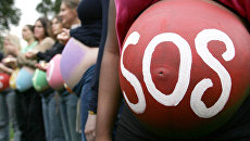 Беременная женщина с надписью SOS на животе на митинге в Лондоне Беременная женщина с надписью SOS на животе на митинге в Лондоне