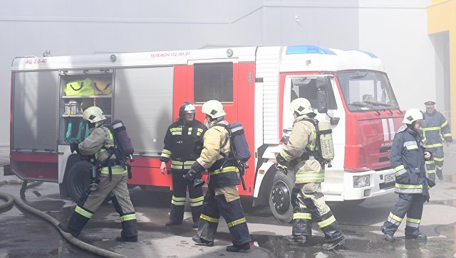 Сотрудники МЧС и пожарная техника перед зданием торгового центра Порт в Казани, где произошло возгорание