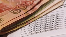 Денежные купюры и квитанция за оплату коммунальных услуг. Архивное фото Денежные купюры и квитанция за оплату коммунальных услуг. Архивное фото