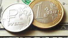 Монеты номиналом один рубль, один евро на банкноте один доллар США. Архивное фото Монеты номиналом один рубль, один евро на банкноте один доллар США. Архивное фото