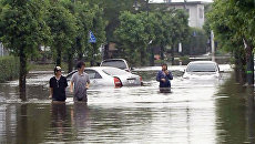 Японцы ходят по улицам затопленных городов по пояс в воде Японцы ходят по улицам затопленных городов по пояс в воде