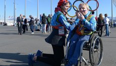 Волонтер в Олимпийском парке Сочи рисует на щеке болельщика российский флаг Волонтер в Олимпийском парке Сочи рисует на щеке болельщика российский флаг